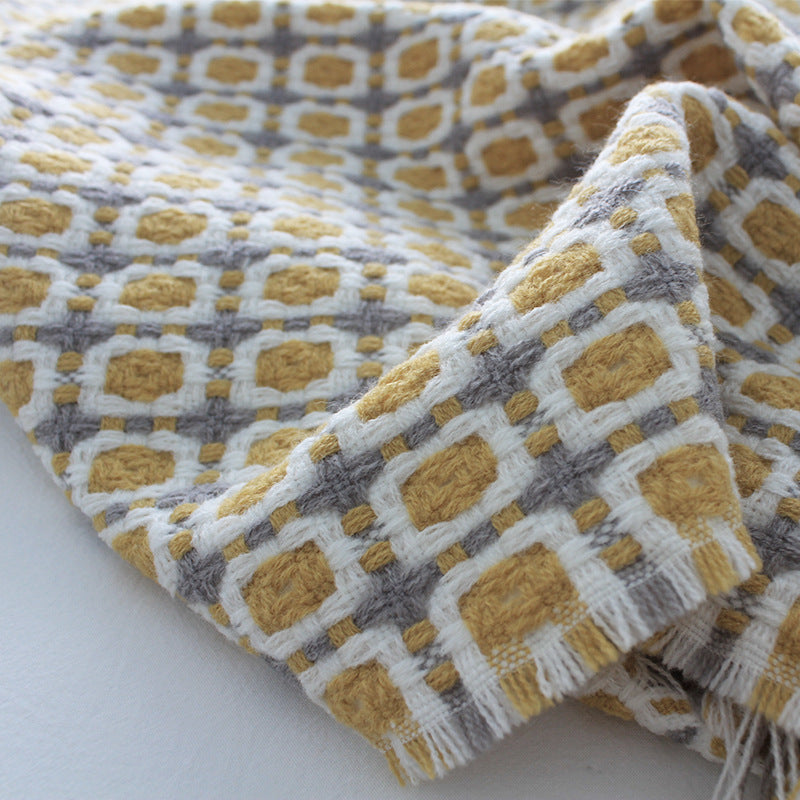 Plaid tricoté à carreaux jaunes posé sur un canapé cosy — MaisonFAME