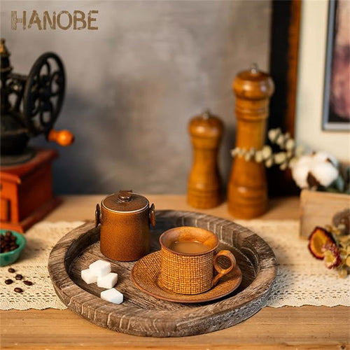 Plateau rond en bois MaisonFAME garni de tasses, d'un moulin à poivre et de bougies sur une table